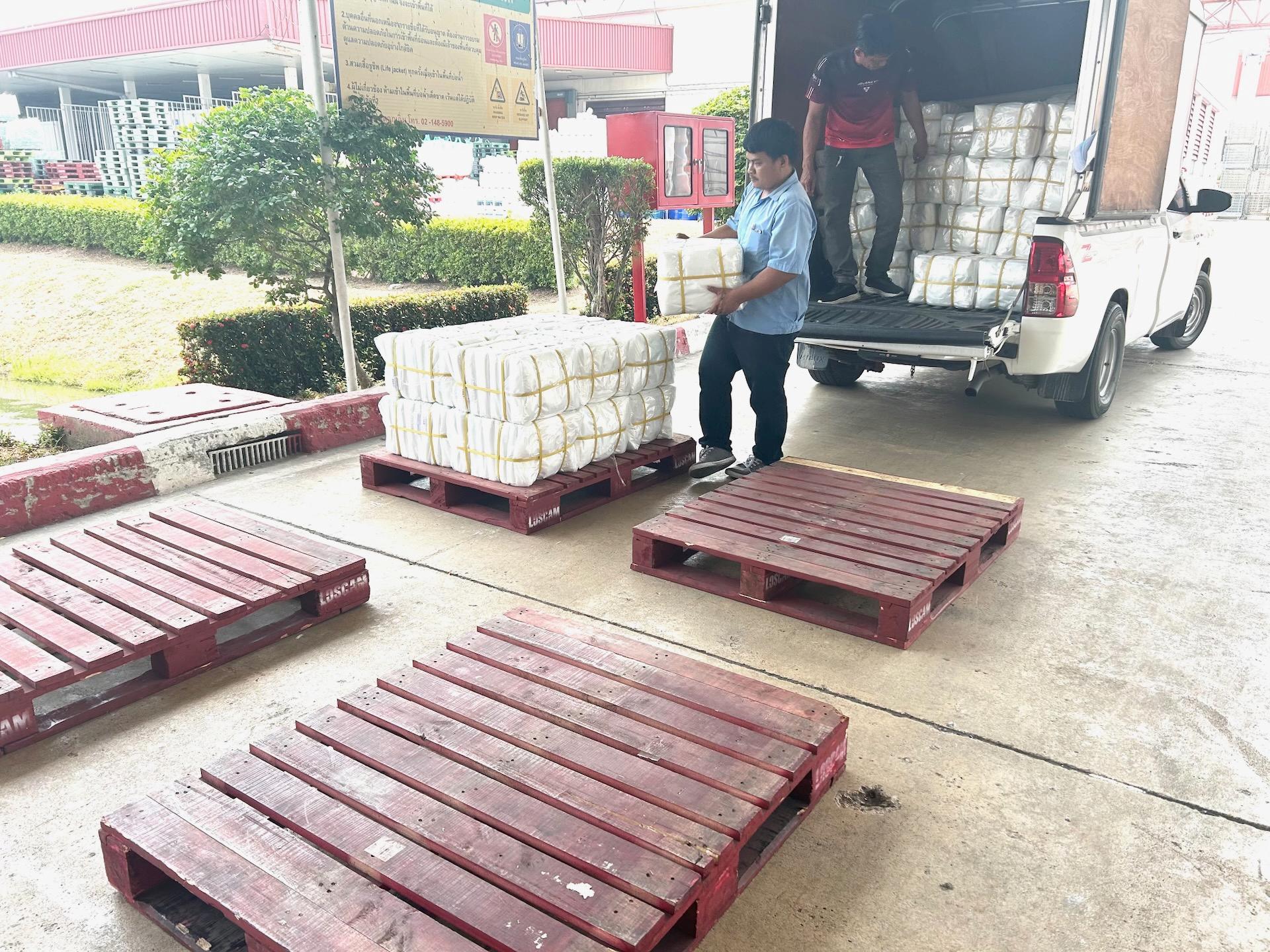 พนักงานกำลังยกสินค้าพลาสติก ลงจากรถ